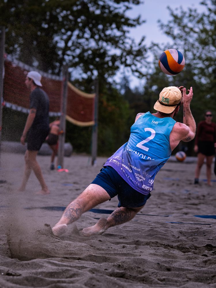Player in a blue jersey launching into a dig