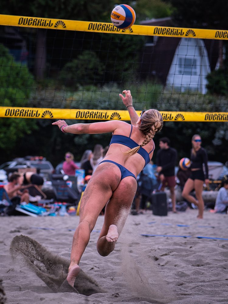 Player chasing down a ball as sand flies