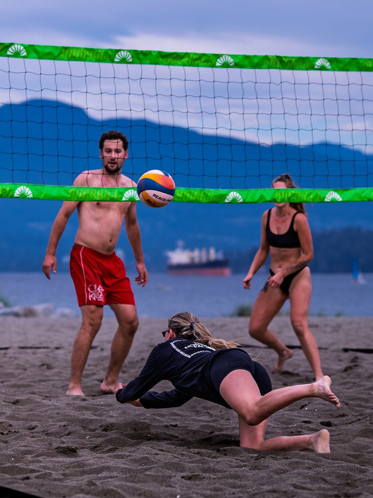 Player sprawling for a dig while her partner watches