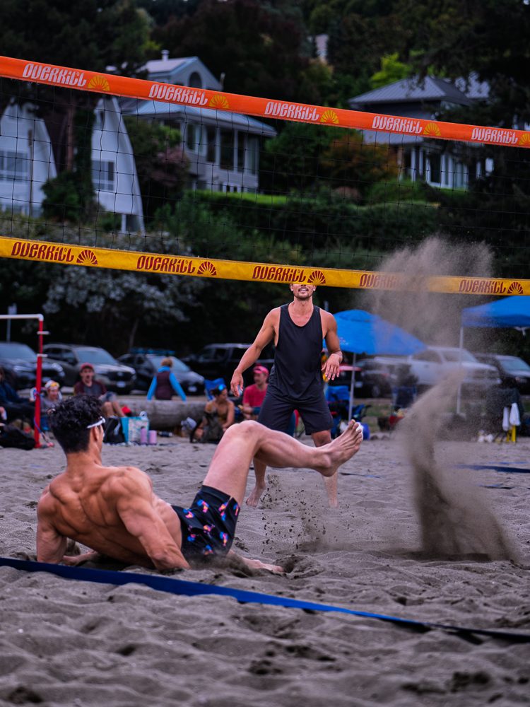 Player diving full stretch as sand sprays