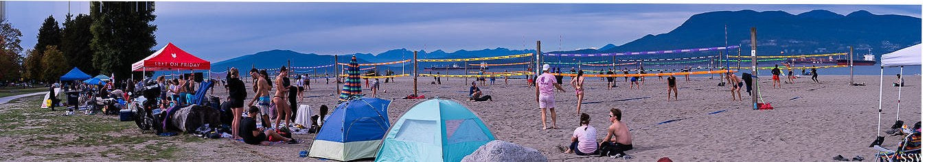 Panorama of a Never Not Sandy tournament with tents, crowd, courts and mountains